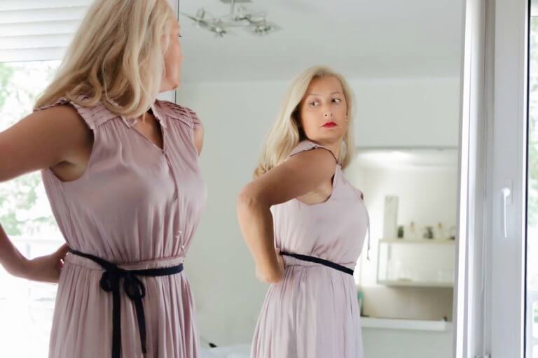 woman in pink dress looking in mirror